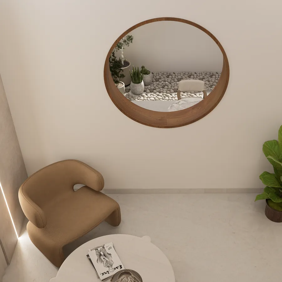 Sculpted armchair beside a round walnut-framed mirror